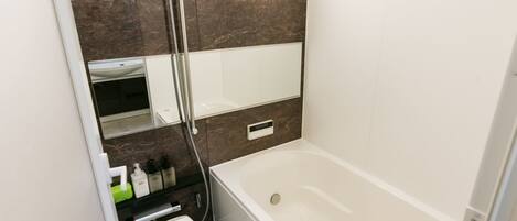Un baño moderno con bañera, ducha y un espejo grande.