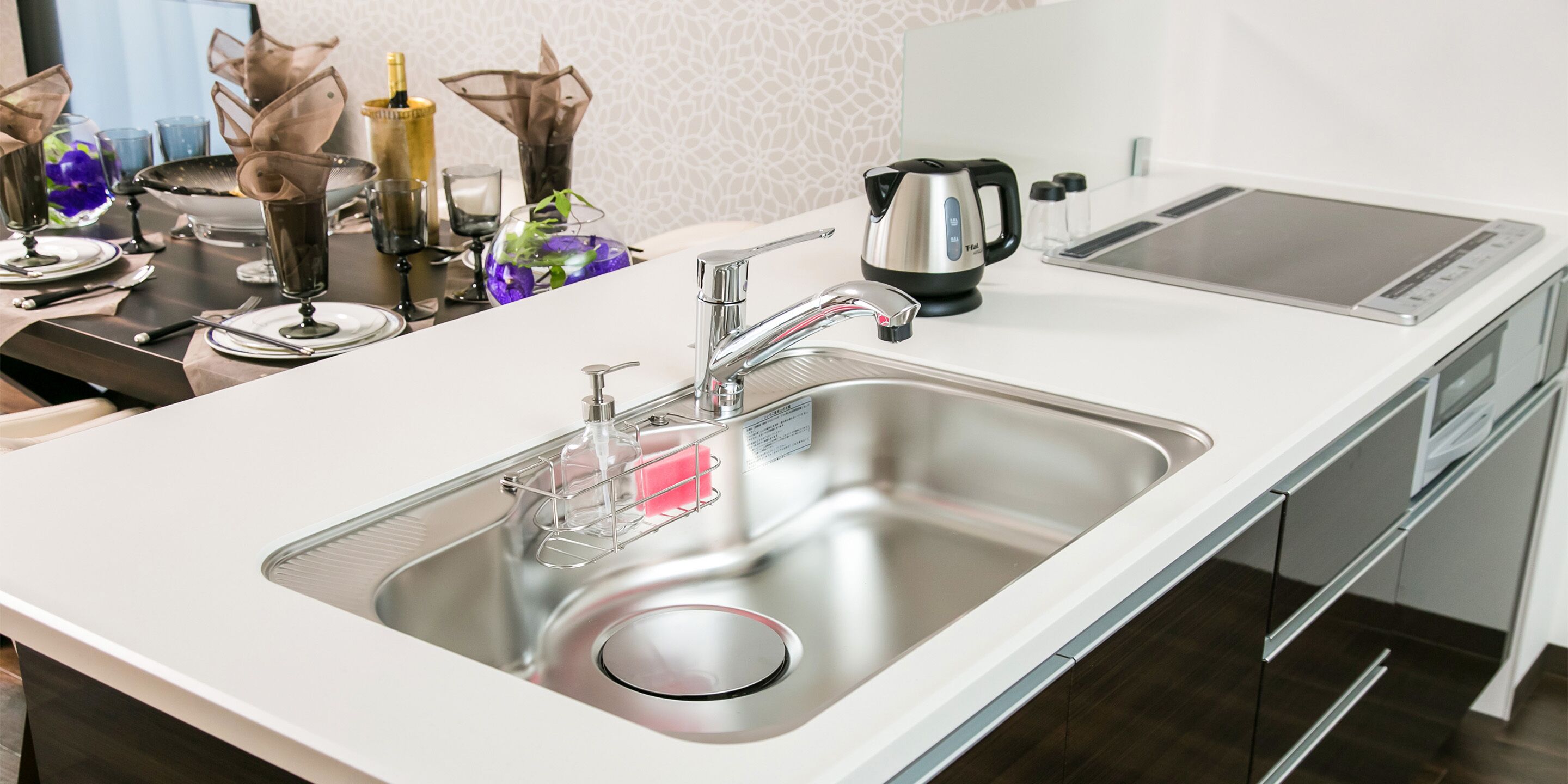 A modern kitchen with a stainless steel sink, a kettle, and a toaster.