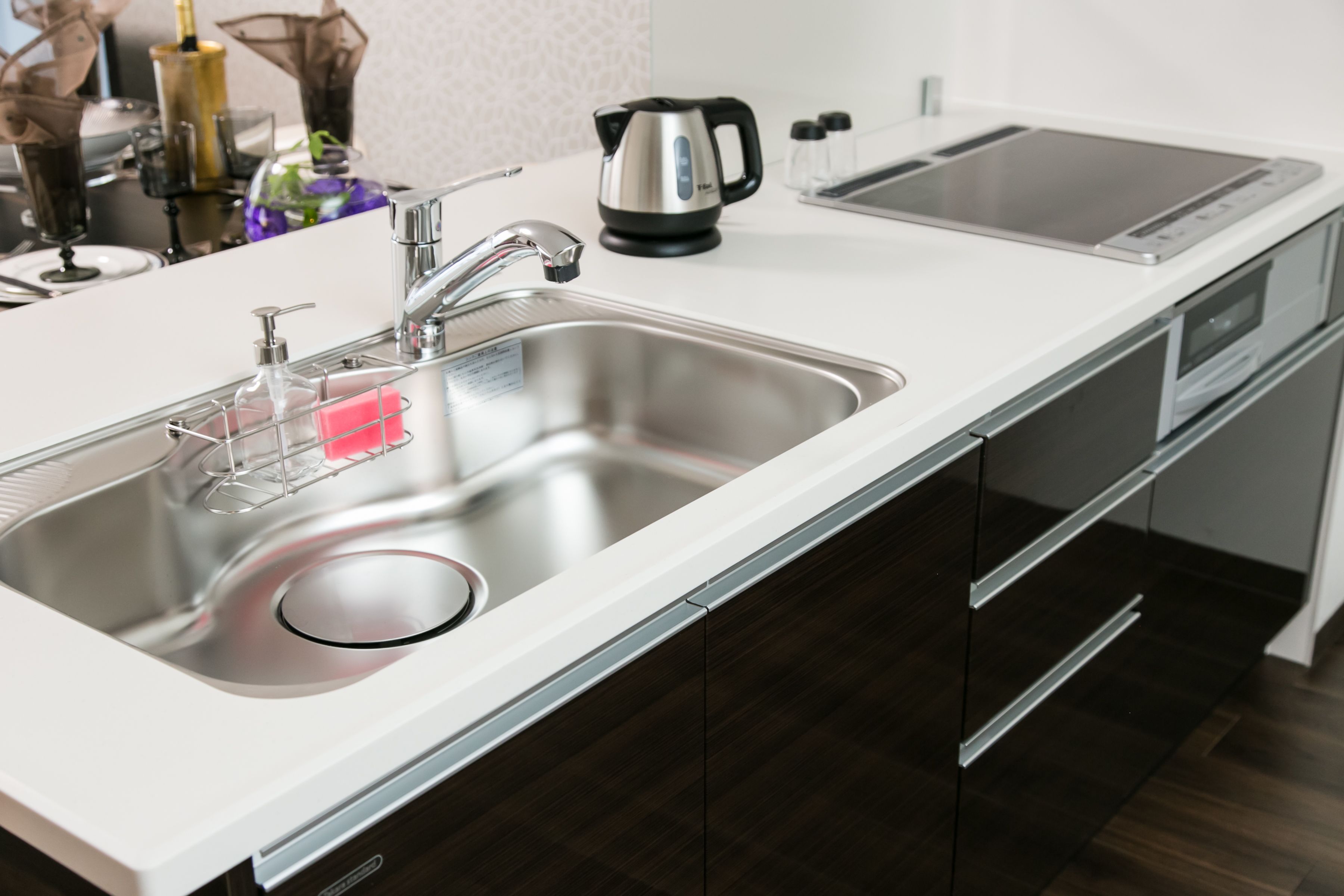 Una cocina moderna con un fregadero de acero inoxidable, un hervidor y un horno empotrado.
