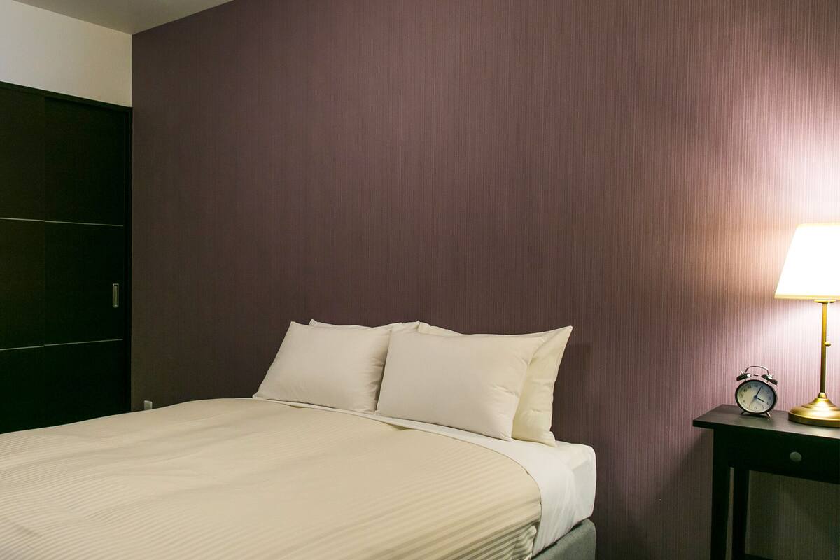 Ein Hotelzimmer mit Bett, Nachttisch mit Lampe und Kleiderschrank.