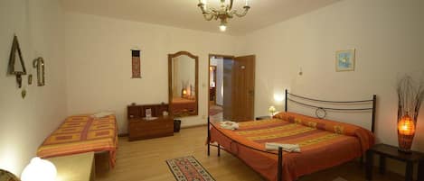 A bedroom with two single beds, a dresser, a mirror, a chandelier, and a bedside table with a lamp.