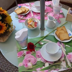 A round table with a floral tablecloth, a pitcher, cups, plates with toast, and a bowl of fruit. - B&B Arabesque (Venice)