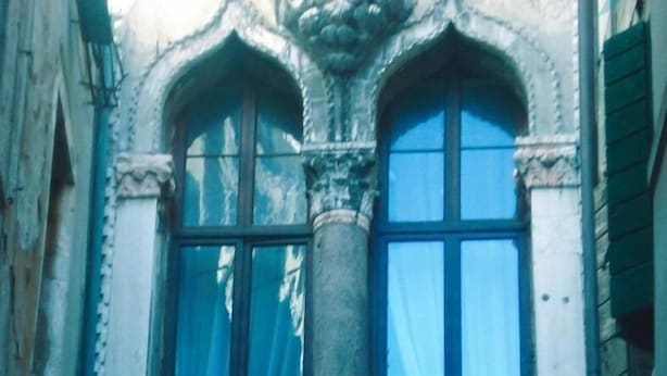 Una ventana de estilo gótico con un pilar de piedra, varios paneles y un arco decorativo.