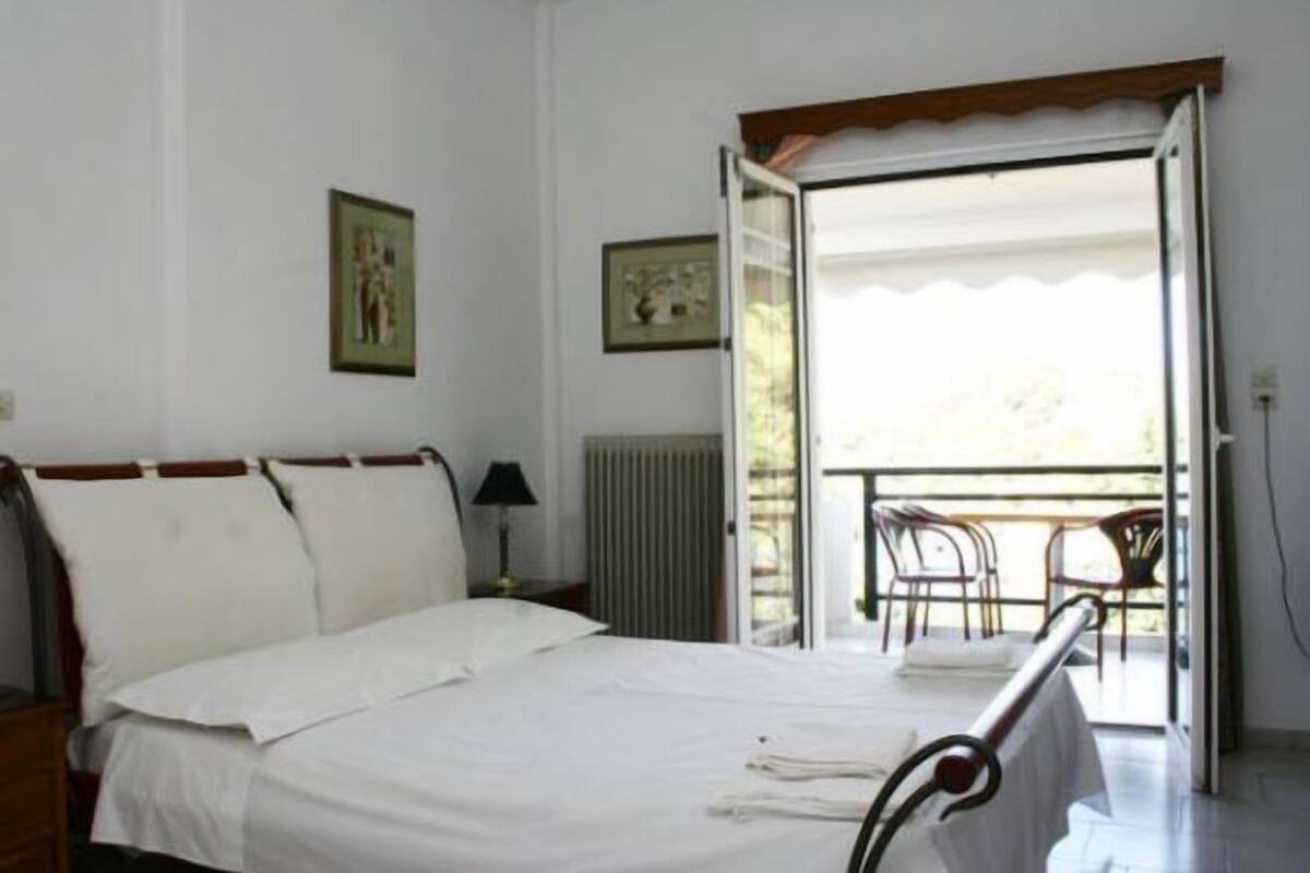 Ein Schlafzimmer mit Bett, Nachttisch, Stuhl und einem Balkon mit Blick.