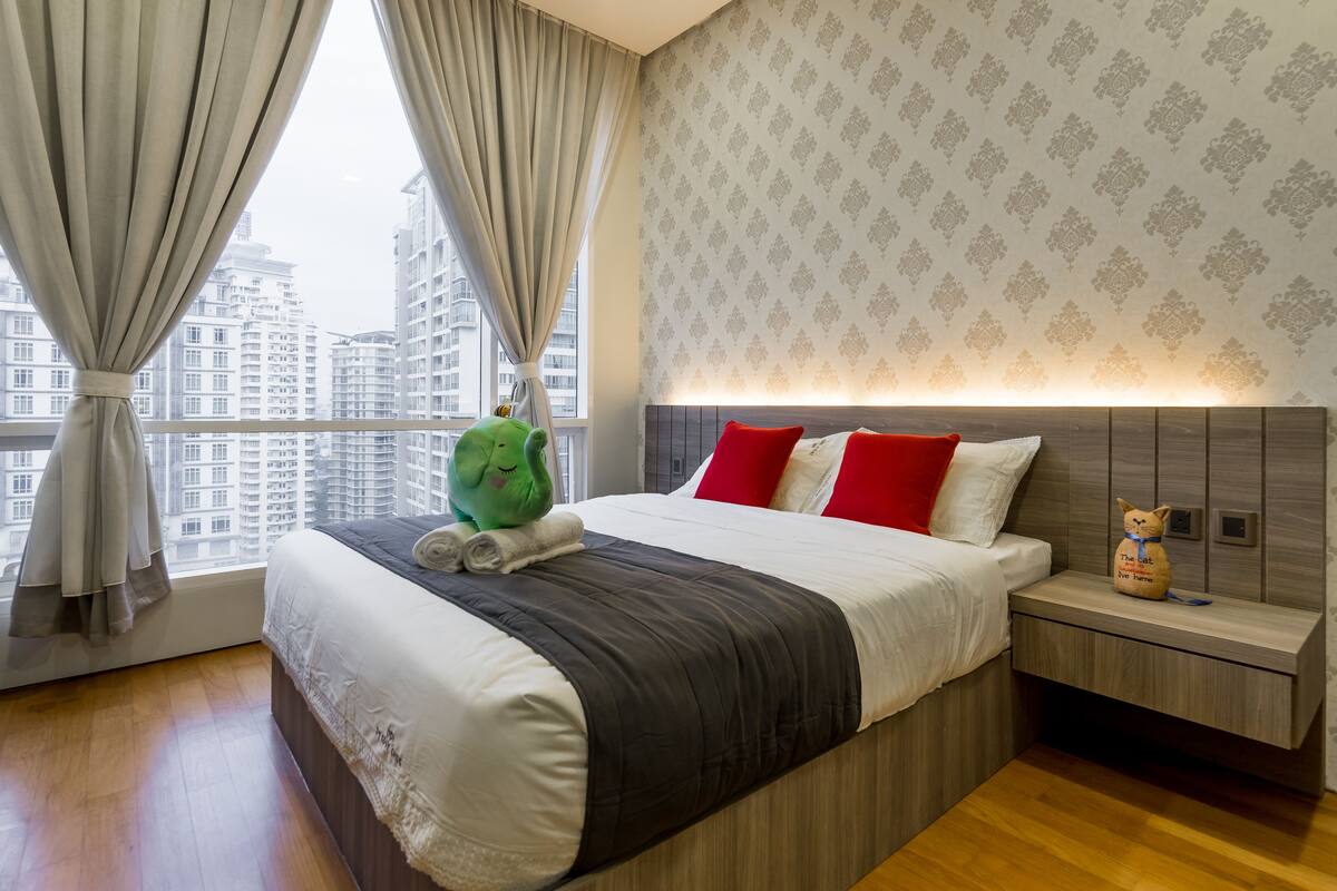 A hotel room with a large bed, a nightstand, and a view of high-rise buildings.