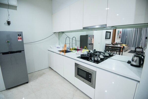 Uma cozinha moderna com armários brancos, forno embutido, micro-ondas e fogão a gás.
