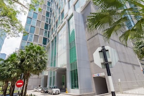 A modern building with a glass facade, a parking sign, and palm trees. - Soho Suites KLCC By Aloha (Kuala Lumpur)