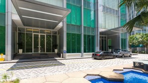 A modern hotel entrance with a glass facade, a pool area with geometric tiles, and a covered walkway. - Soho Suites KLCC By Aloha (Kuala Lumpur)