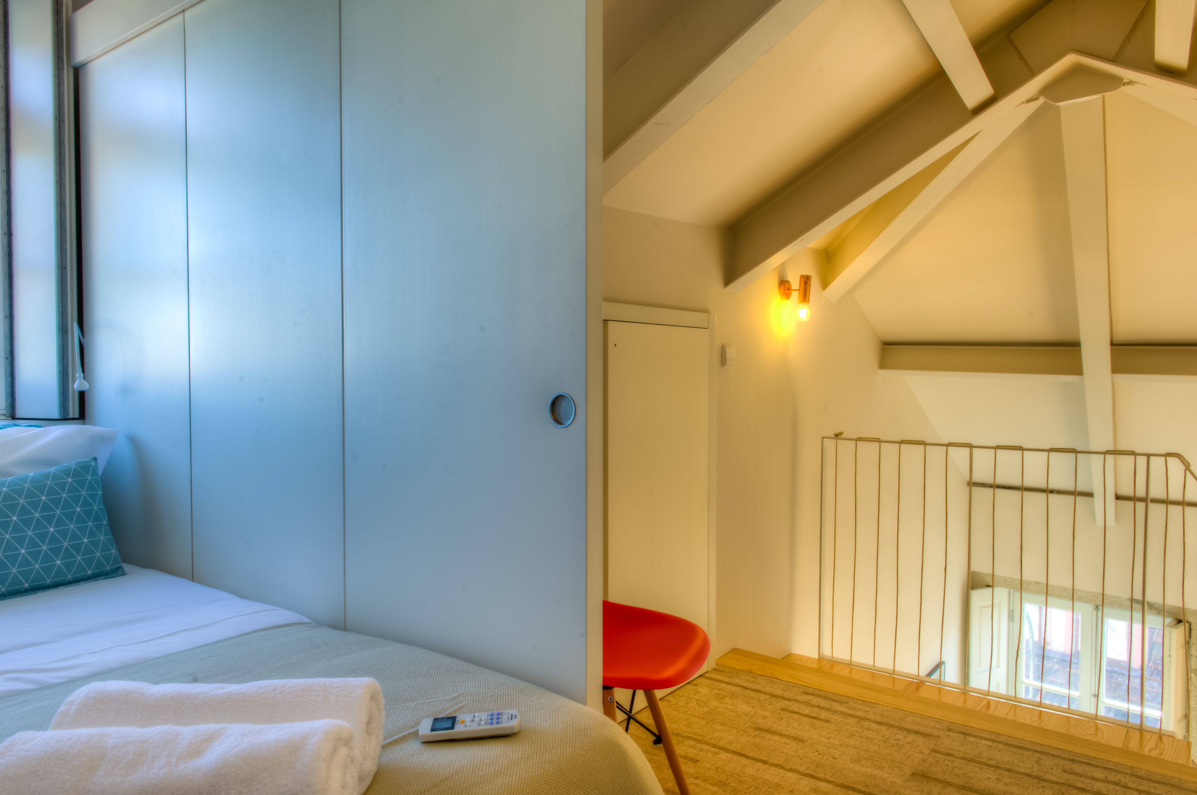 Une chambre à coucher avec un lit, une chaise rouge, une fenêtre et une porte.