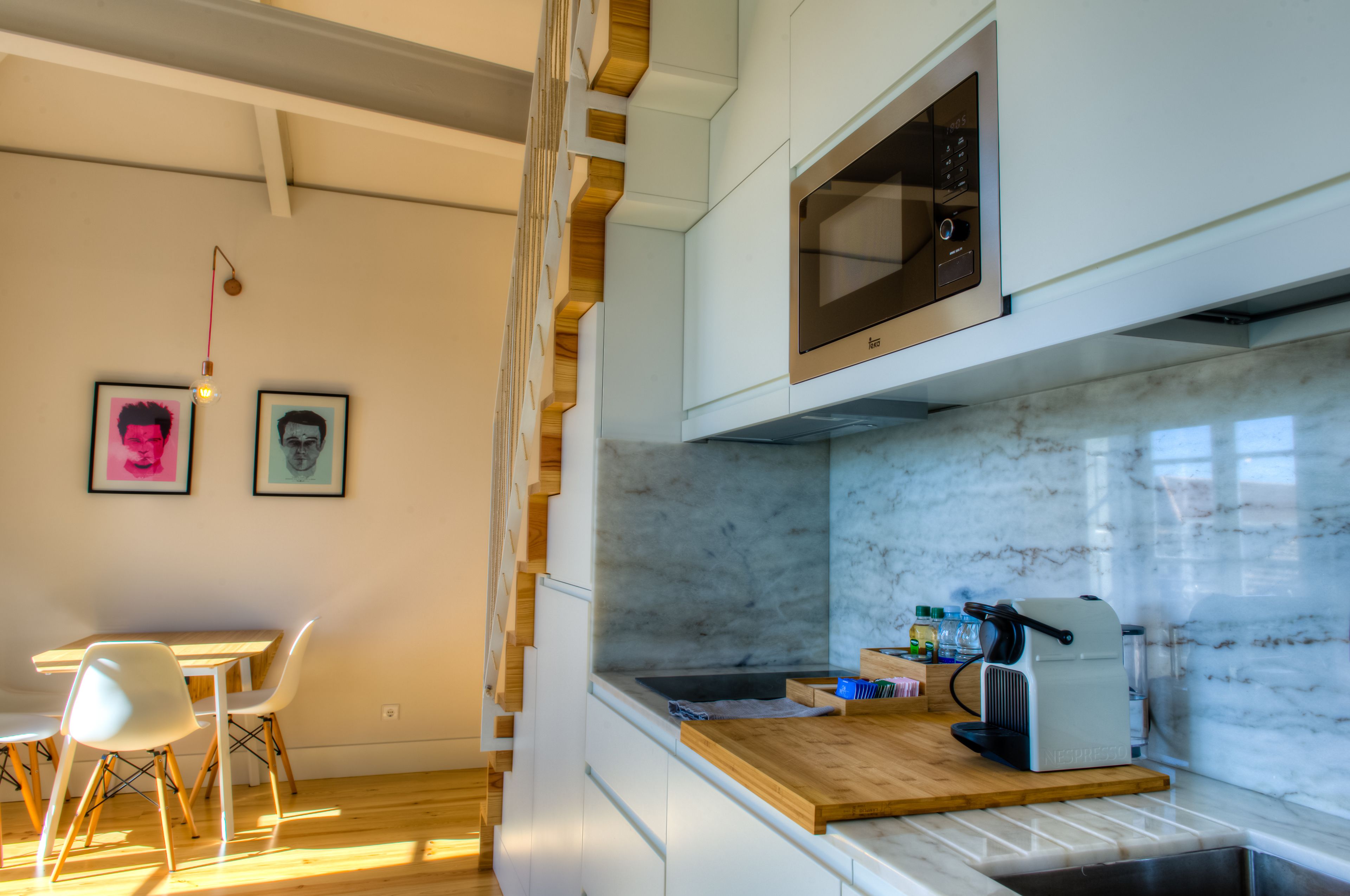 Una cocina moderna con armarios blancos, un microondas integrado y una encimera de madera.