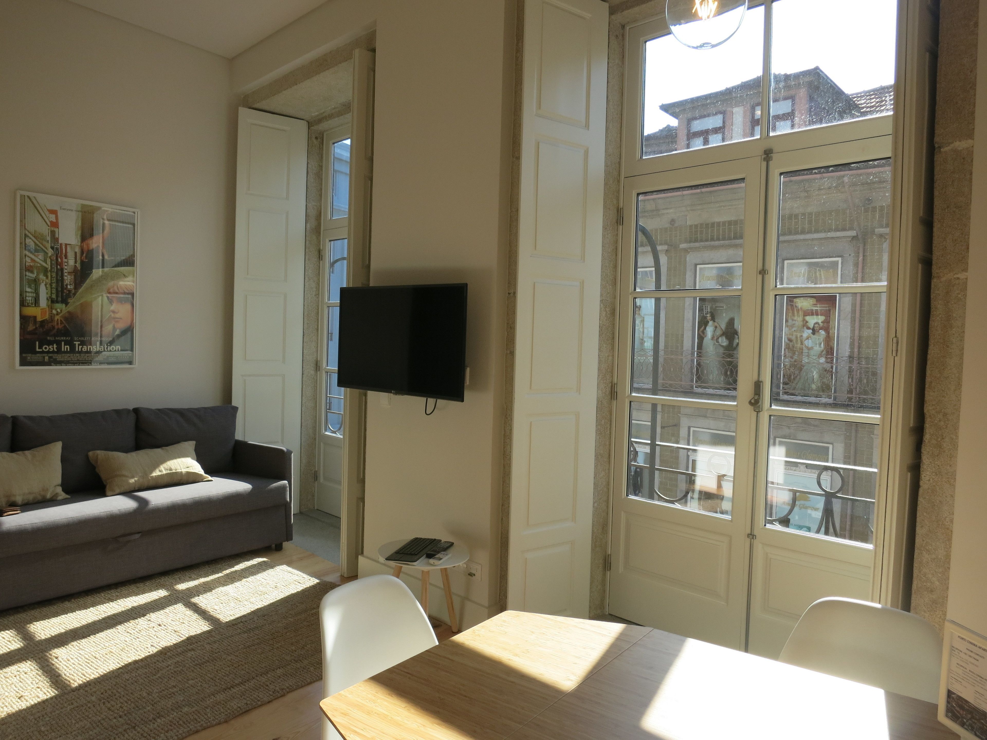 Un salon avec un canapé gris, une table en bois et un téléviseur fixé au mur.
