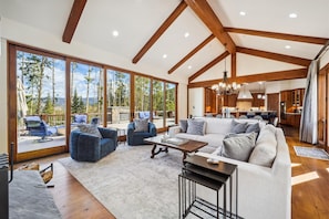 Relax in a spacious living area with a high ceiling, featuring a seating area with sofas and armchairs, and a kitchen with wooden cabinets.