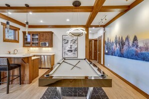 Enjoy a game of pool in this stylish room featuring a pool table, large painting, and comfortable seating.
