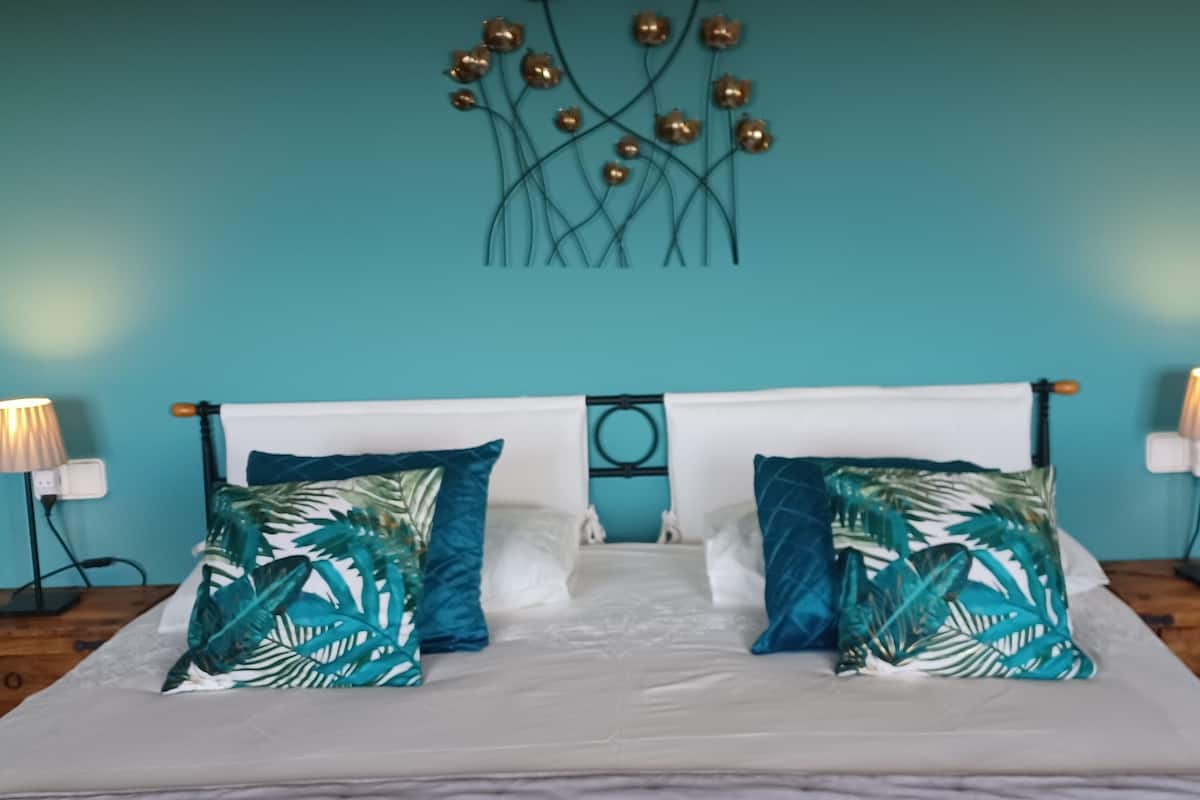 A bed with white bedding, two nightstands with lamps, and a wall art piece above the bed.