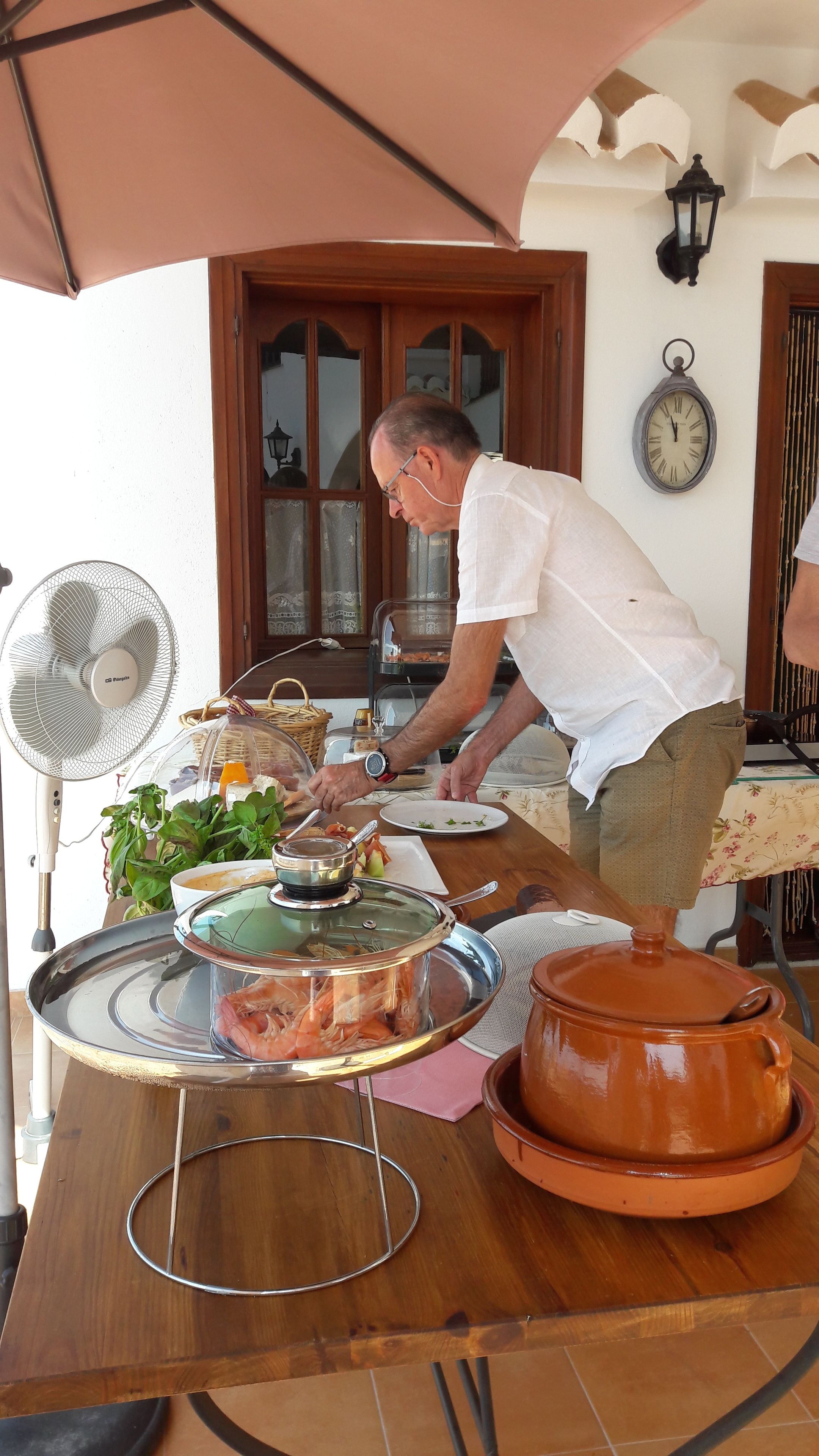 Un comedor con una mesa dispuesta para una comida, un ventilador y un reloj en la pared.