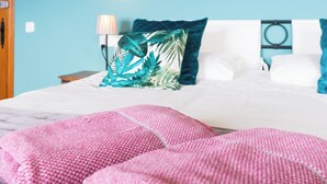 A bedroom with a bed, pillows, a wall art piece, and a lamp.