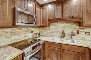 Kitchen features a stainless steel microwave, toaster, and sink with a faucet, along with a small potted plant.