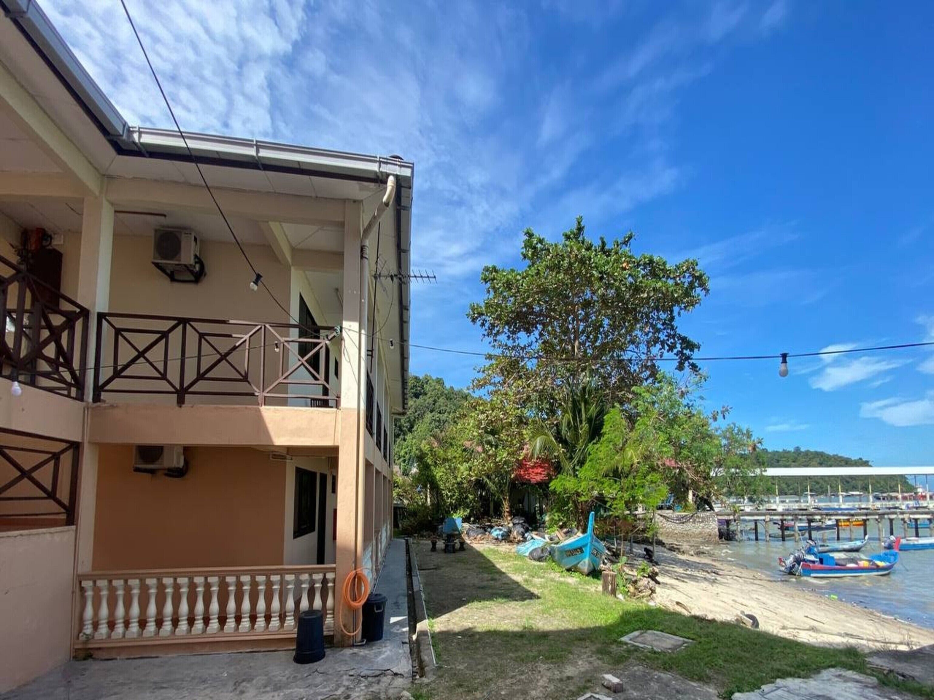 A two-story building with a balcony, a clear sky, and a river with boats.