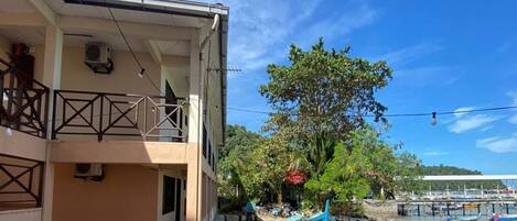 A two-story building with a balcony, a clear sky, and a river with boats.