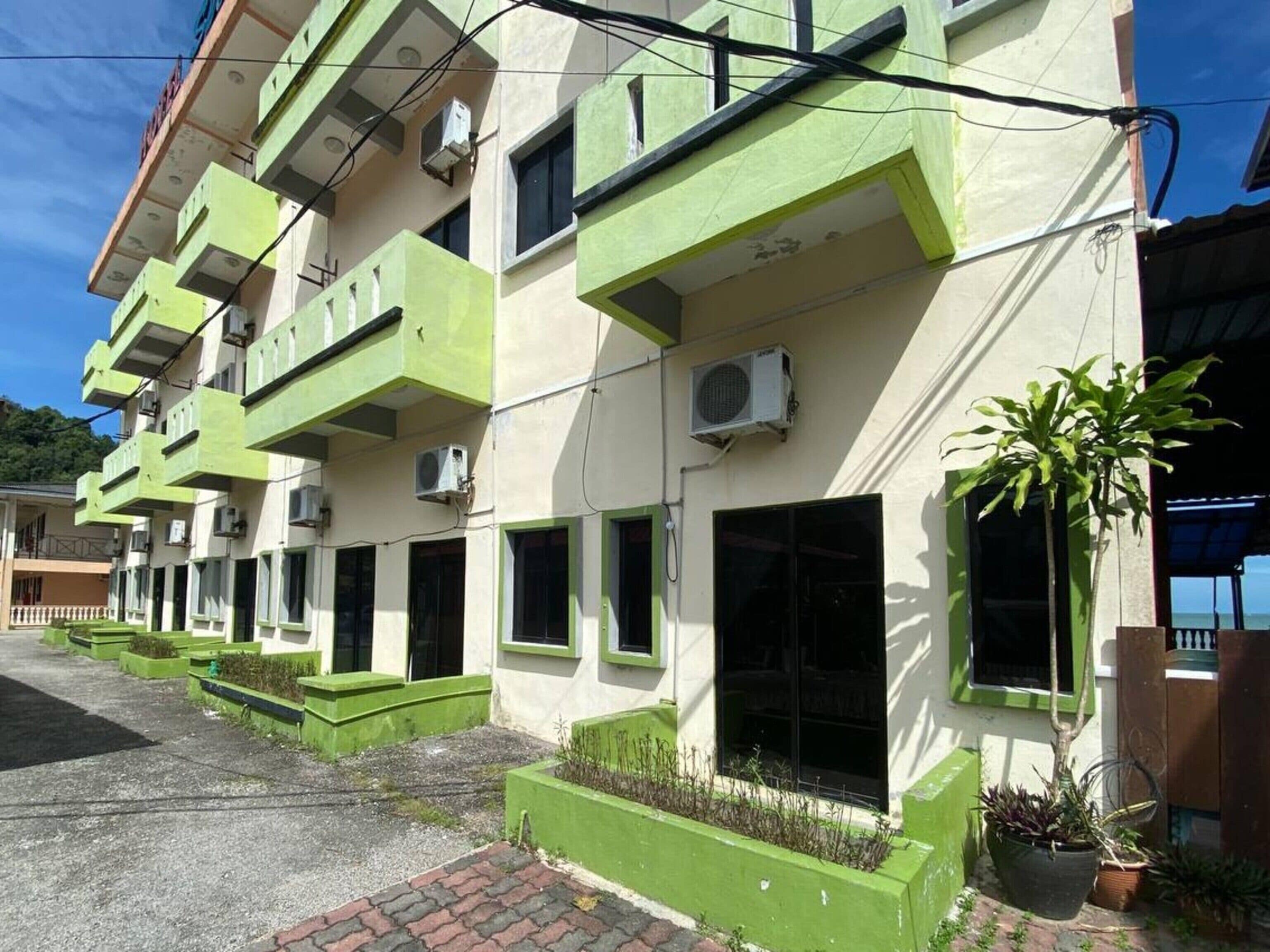 A multi-story building with balconies, air conditioning units, and potted plants.