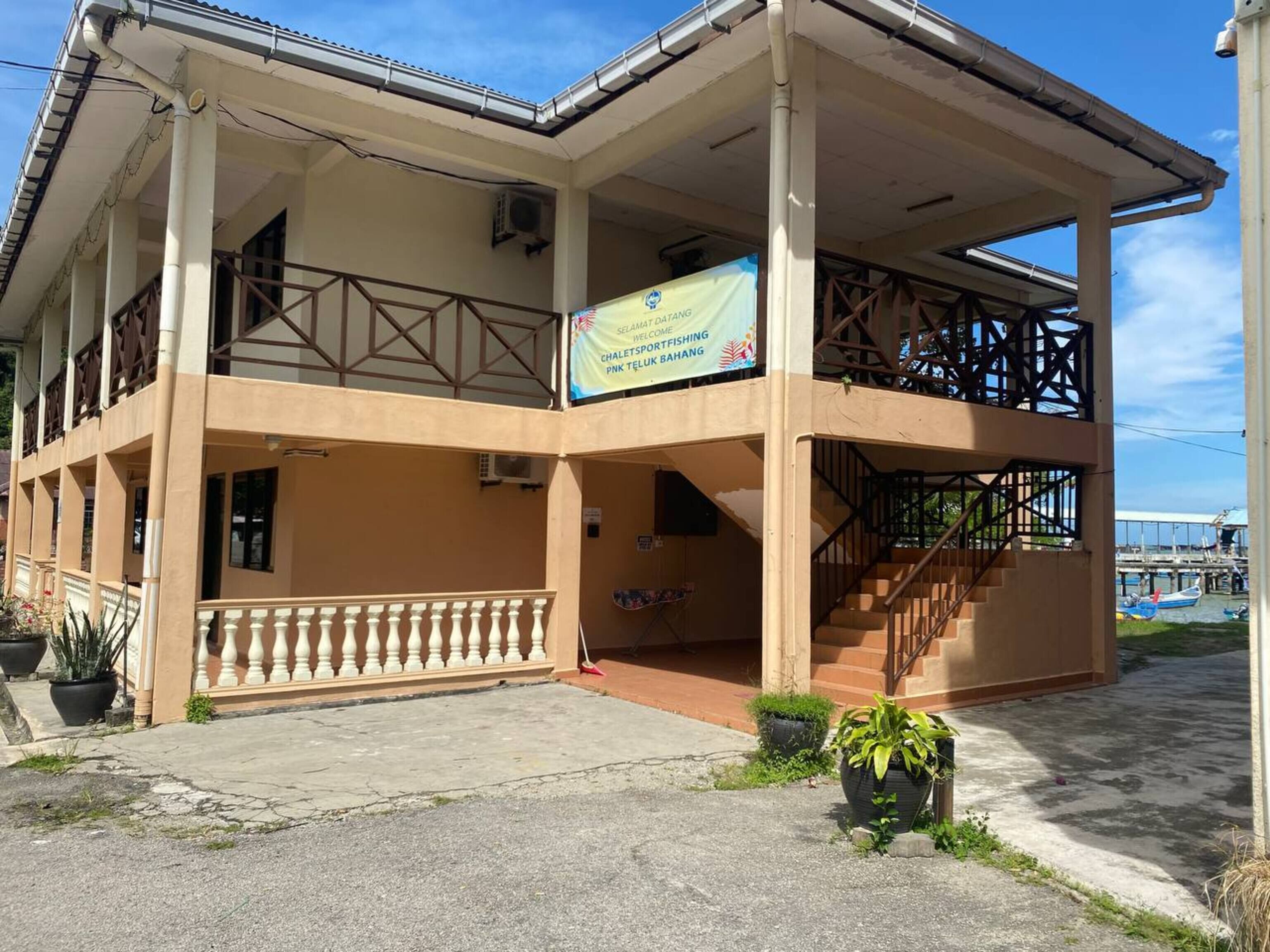 A two-story building with a balcony, a staircase, and a signboard.