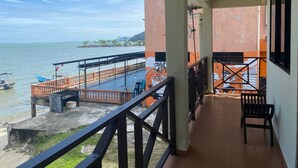 Un balcón con vista al mar, barandilla de madera y un banco.