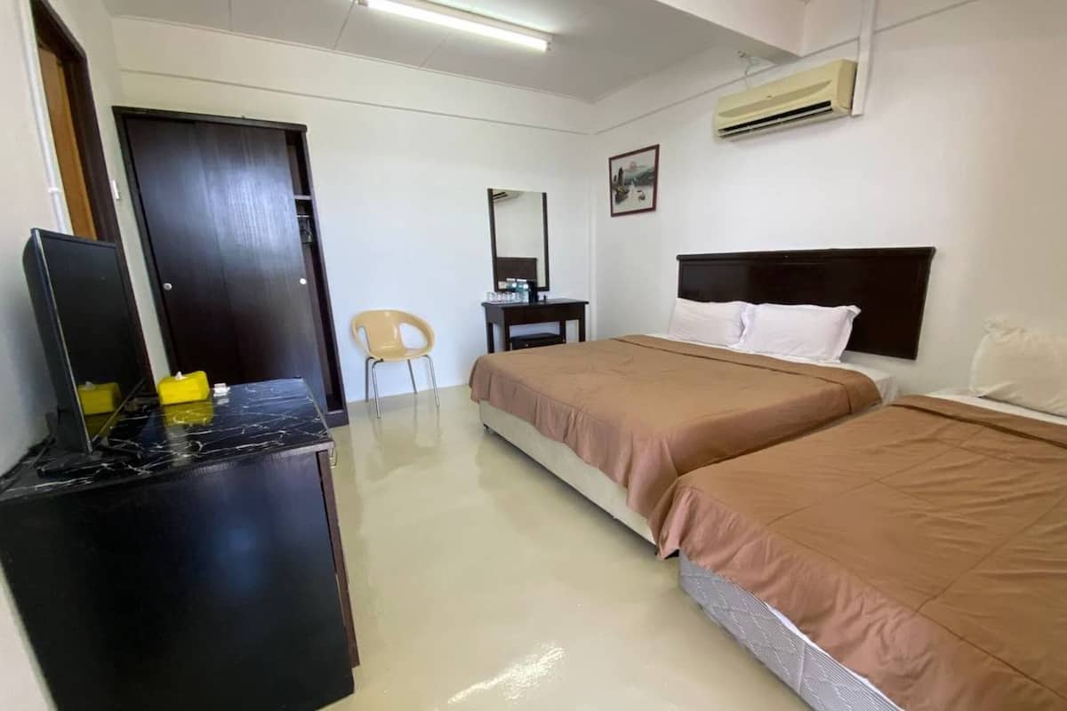 A hotel room with two beds, a desk, a chair, and an air conditioning unit.