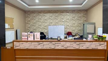 A reception desk with a stone-patterned wall, a whiteboard, and various informational materials.