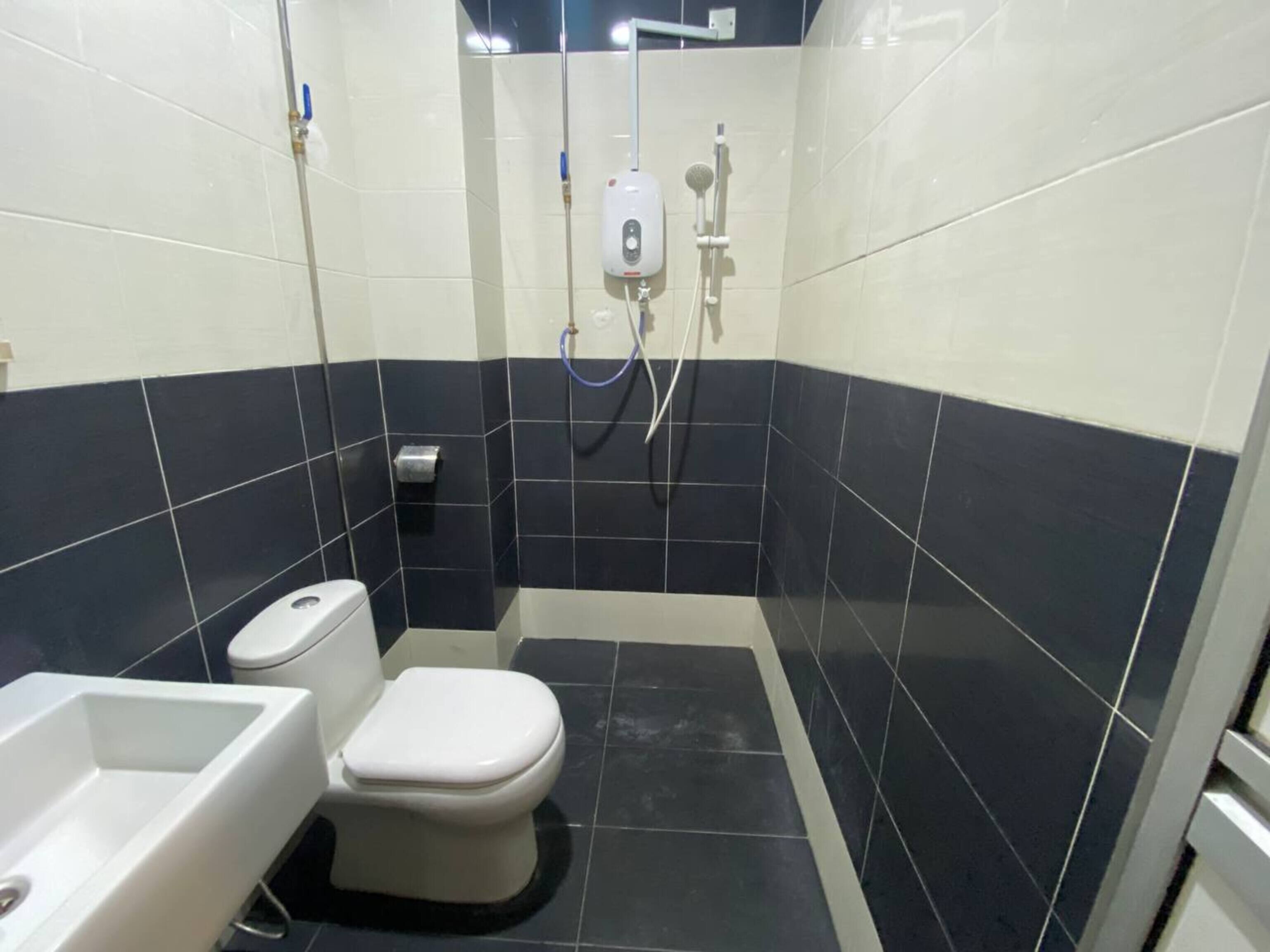 A small bathroom with a toilet, a sink, and a shower area.
