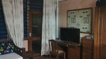 Un dormitorio con una cama, un escritorio, una silla, un televisor y un armario.