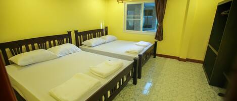A hotel room with two beds, a window with curtains, and a wardrobe.