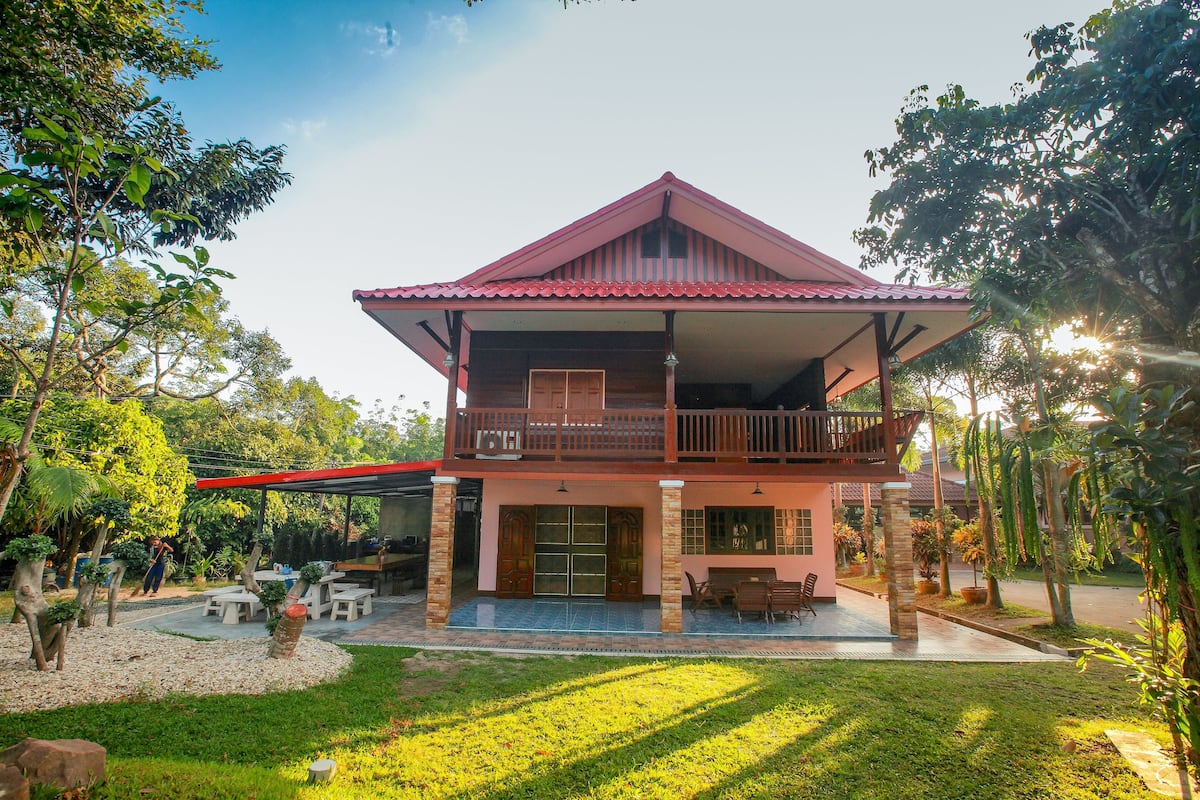 A two-story house with a balcony, a covered patio, and a well-maintained garden.