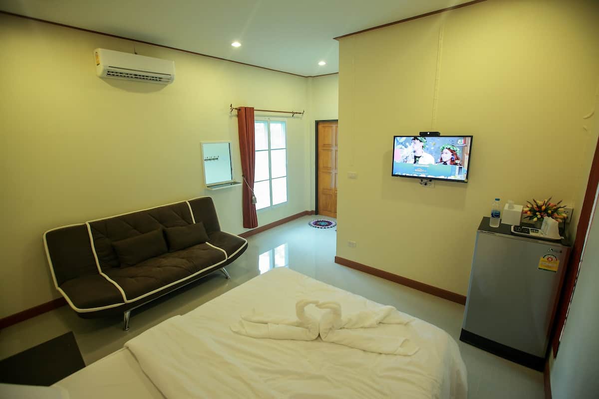 A hotel room with a bed, a sofa, a television, and a refrigerator.