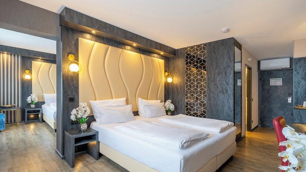 A modern hotel room with a large bed, bedside tables, a mirror, and a view of the hallway. - PLAZA INN Bruchsal (Bruchsal)