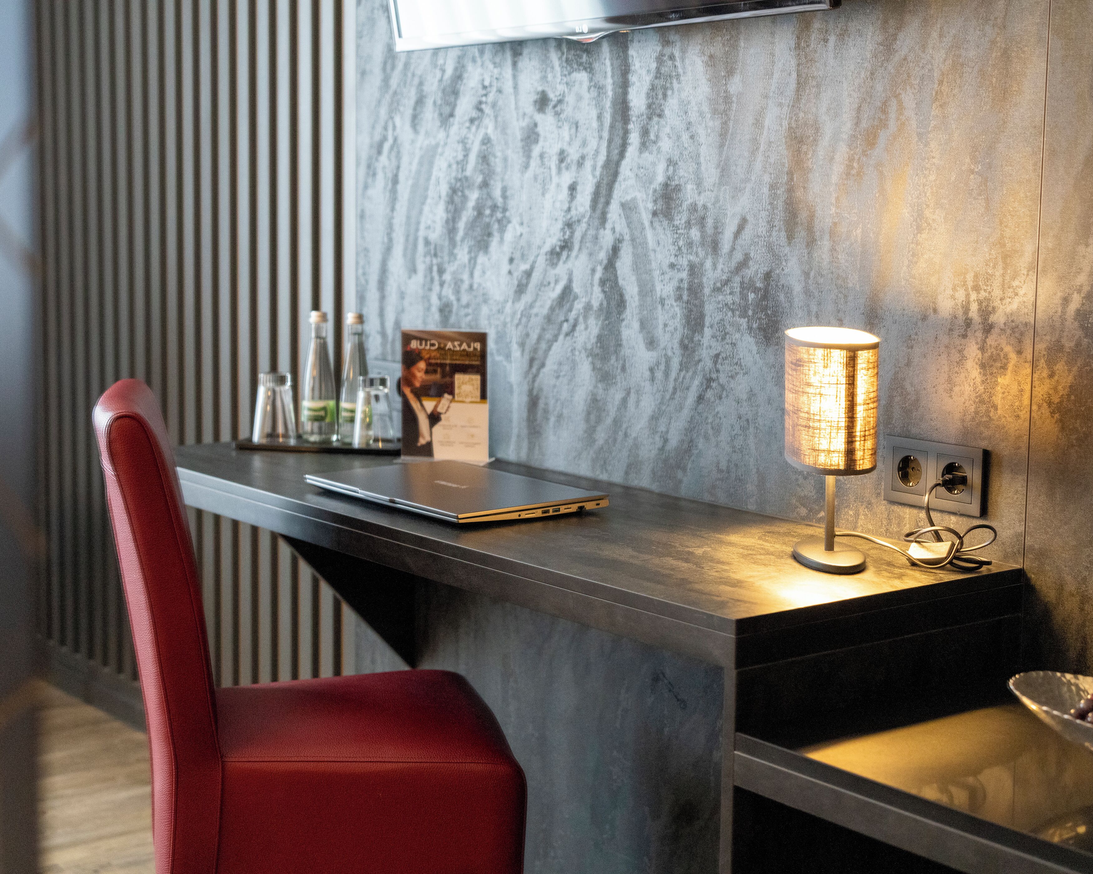 A modern workspace with a laptop, a lamp, and a chair.