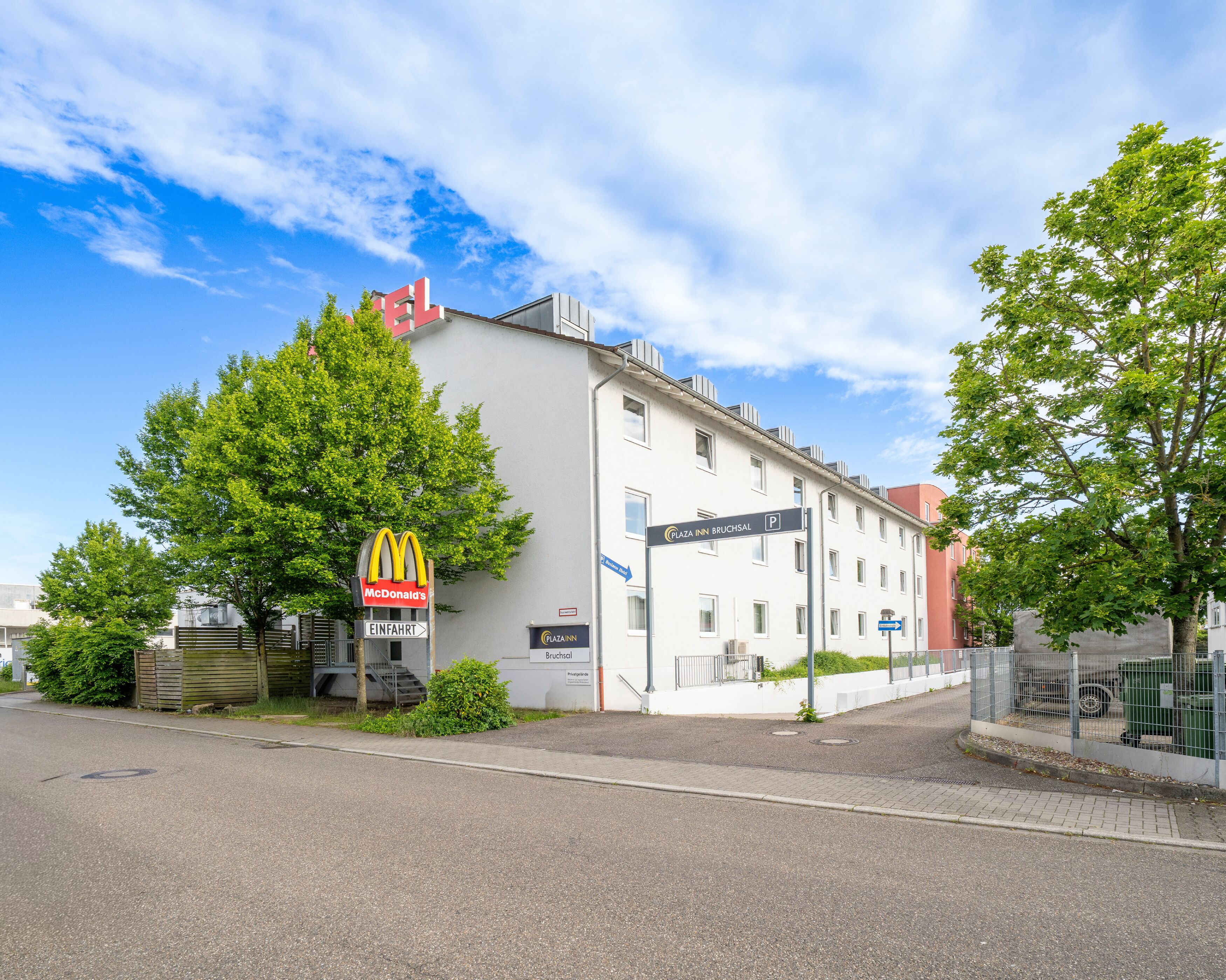A building with a McDonald's sign, a sign for Plaza Inn Bruchsal, and a parking sign.