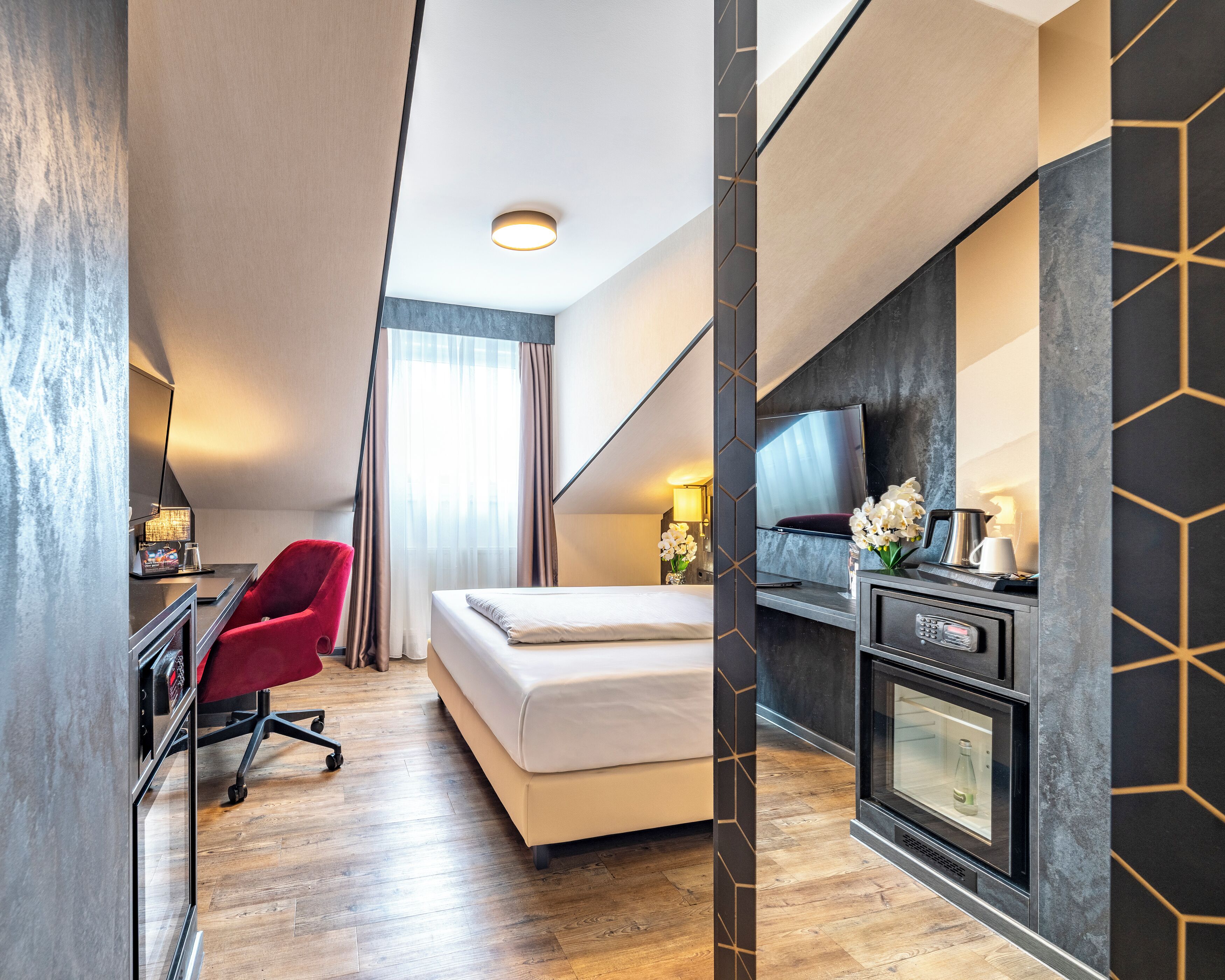 Habitación de hotel con cama, escritorio con silla, televisor, chimenea y un amplio ventanal con cortinas.