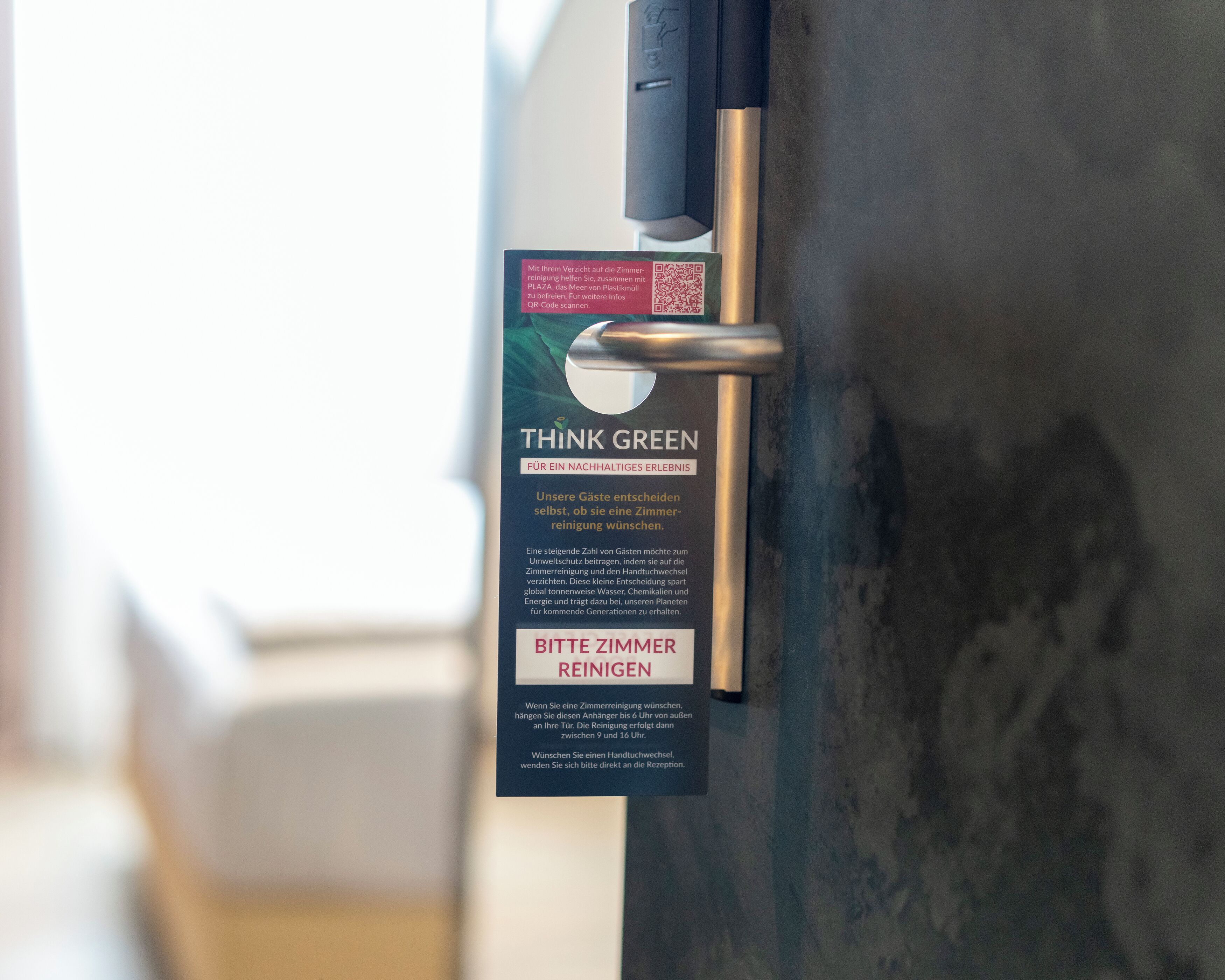 A door with a QR code and a sign that reads 'THINK GREEN' and 'BITTE ZIMMER REINIGEN' in German.