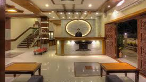 A lobby with a reception desk, a staircase, and seating areas. - The White Lake Hotel (Tansen)