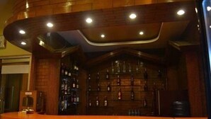 A bar area with a curved wooden counter and shelves of bottles. - The White Lake Hotel (Tansen)