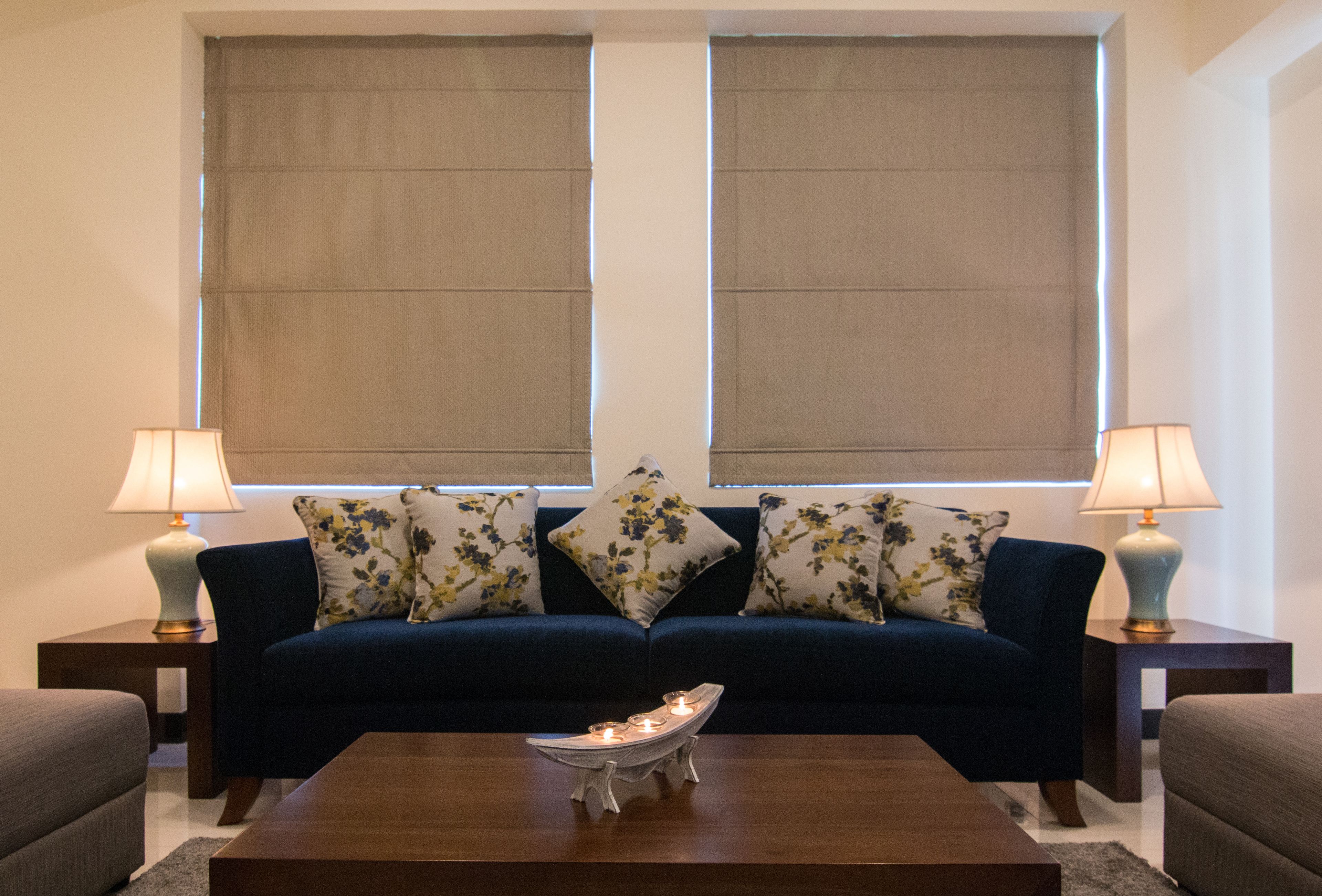 Ein Wohnzimmer mit einem dunkelblauen Sofa, zwei gleichgestimmten Lampen und einem dekorativen Tisch davor.