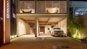 A modern building with a car parked in front, a visible entrance, and a sign on the left. - Rococo Residence (Colombo)
