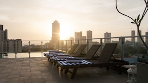 A rooftop terrace with lounge chairs and a view of a city skyline at sunset. - Rococo Residence (Colombo)