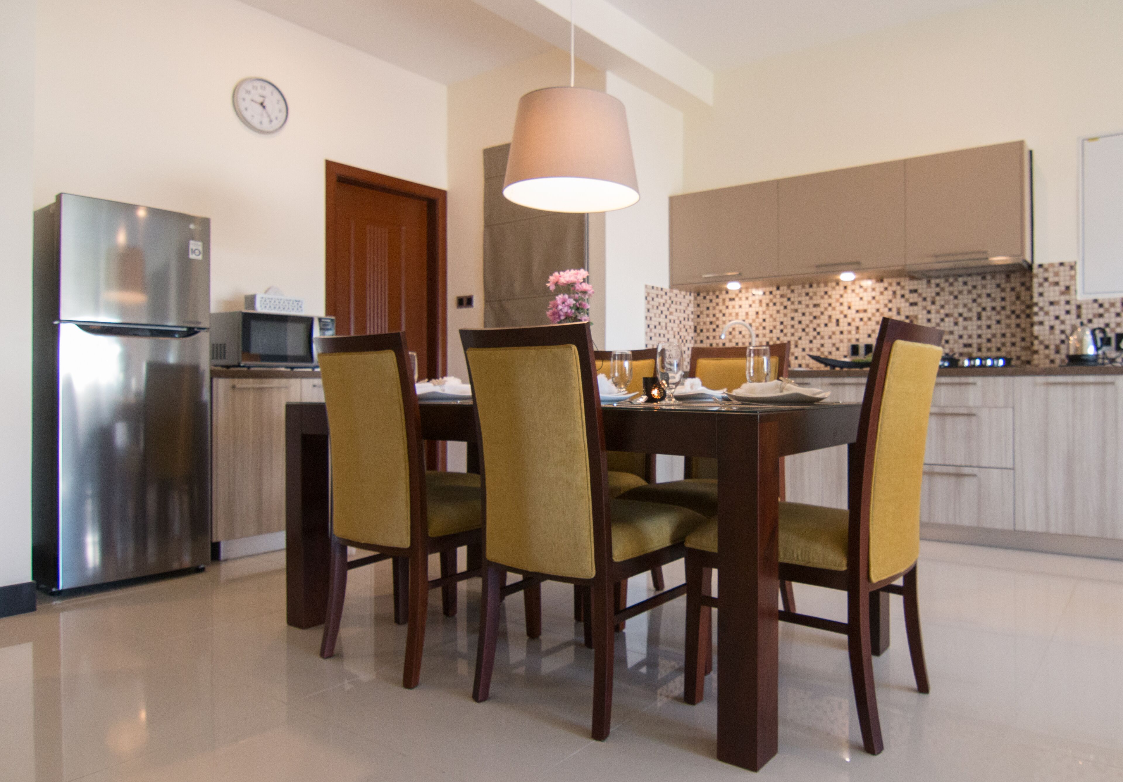 A modern kitchen with a dining table, chairs, and a clock on the wall.