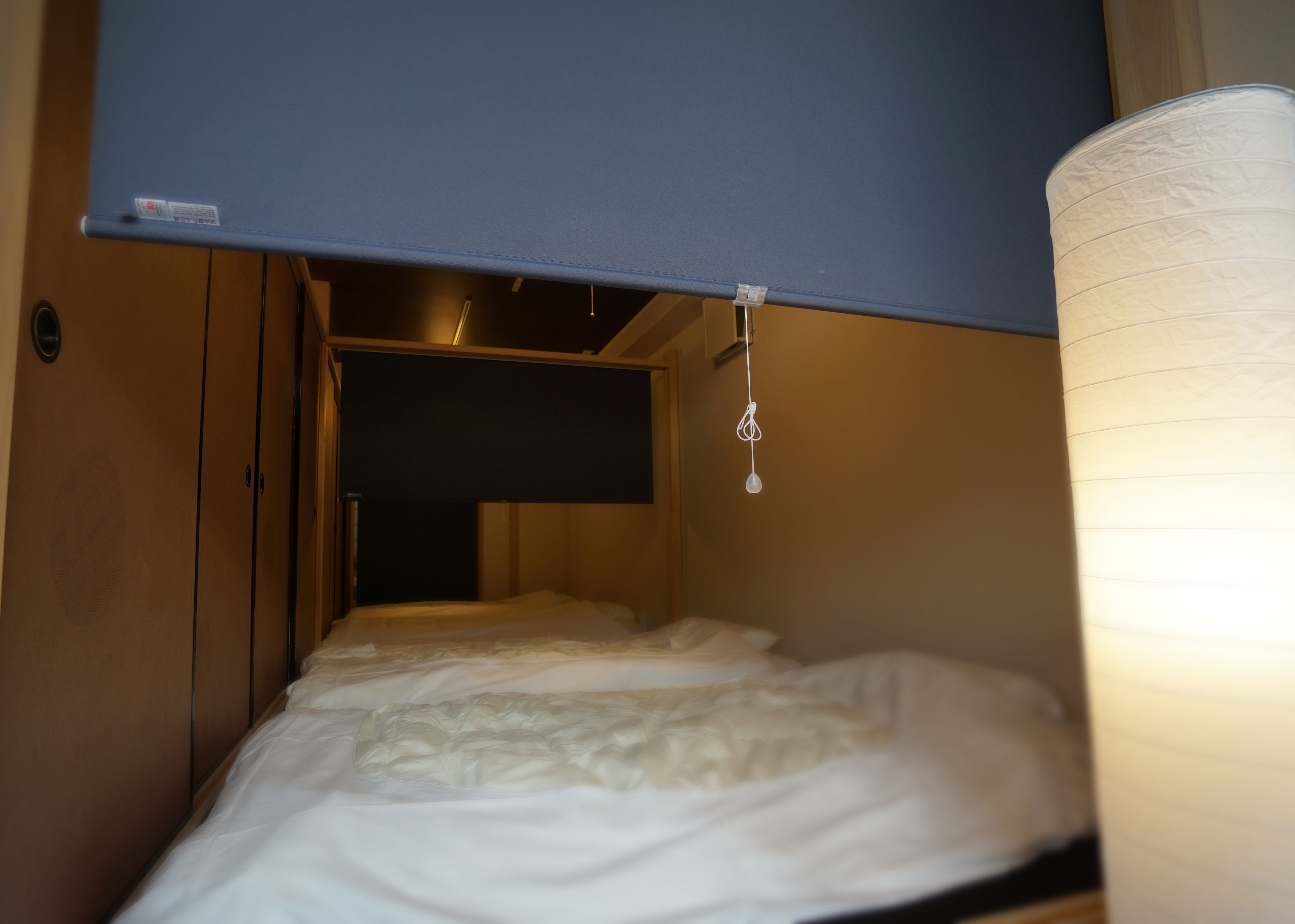 A bunk bed with a pull-up ladder, a bedside table, and a hanging light fixture.