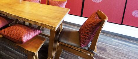 A wooden dining table with matching chairs and red cushions.