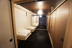 A narrow hallway with bunk beds, wooden lockers, and a checkered floor.