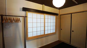 A traditional Japanese room with sliding doors, a shoji screen window, and a hanging wooden rack.