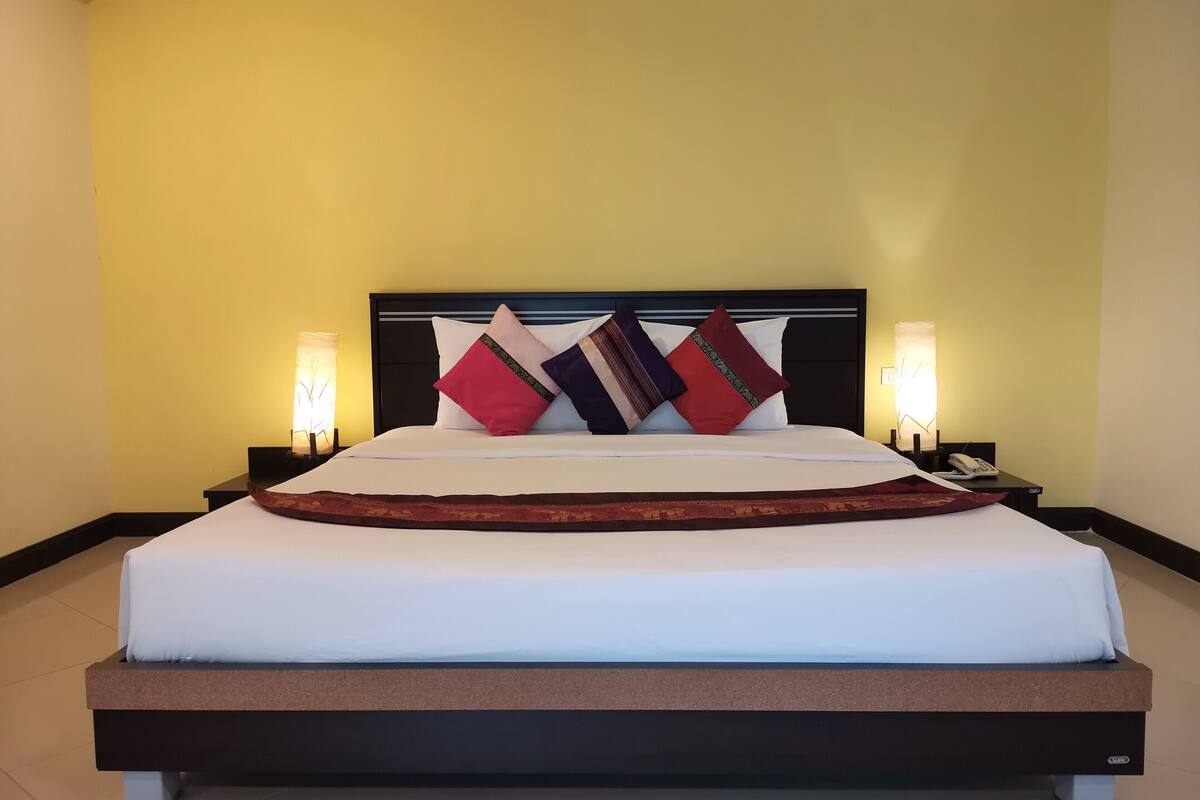A hotel room with a large bed, two bedside tables with lamps, and a headboard.