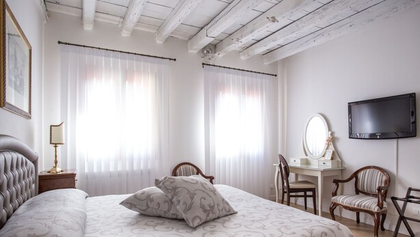 Una camera da letto con un letto grande, una scrivania con una sedia, una televisione e uno specchio.
